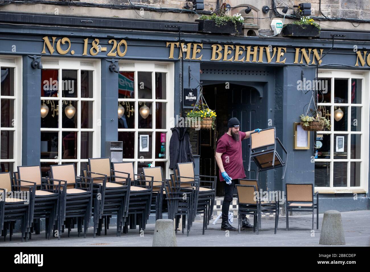 A member of staff at The Beehive Inn in the Grassmarket, Edinburgh, cleans and puts away the chairs following the pub's closure due to the coronavirus outbreak. Stock Photo