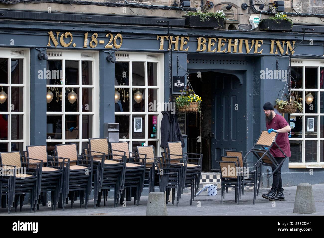 A member of staff at The Beehive Inn in the Grassmarket, Edinburgh, cleans and puts away the chairs following the pub's closure due to the coronavirus outbreak. Stock Photo