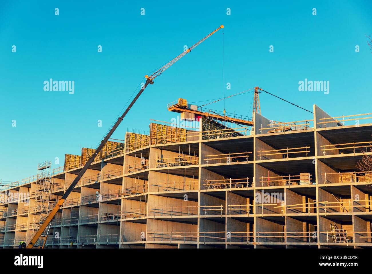 housing development - workers and cranes working on apartment building construction site Stock Photo