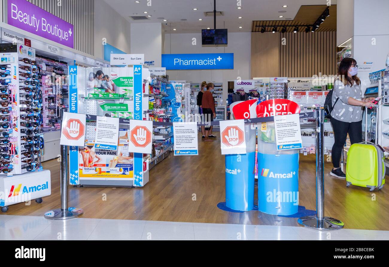 Coronavirus warning signs and safety barriers at an Amcal pharmacy at the international