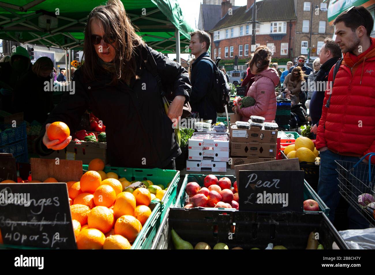 London, UK. 21st March 2020.  at Venn Street in Clapham shoppers appreciate fresh fruit and vegetables available at the weekly Saturday market. However, very few wore face masks or observed social distancing advice. Credit: Anna Watson/Alamy Live News Stock Photo