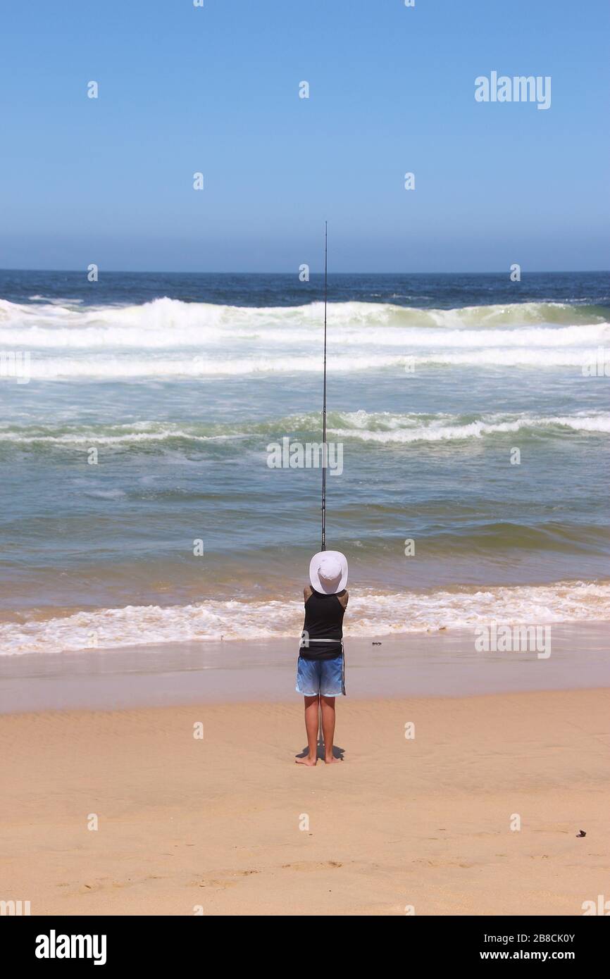 Plettenberg Bay, South Africa, Africa - March 1, 2020: Angling boy and the wild Pacific ocean. On the beach of Plettenberg Bay, South Africa. Stock Photo