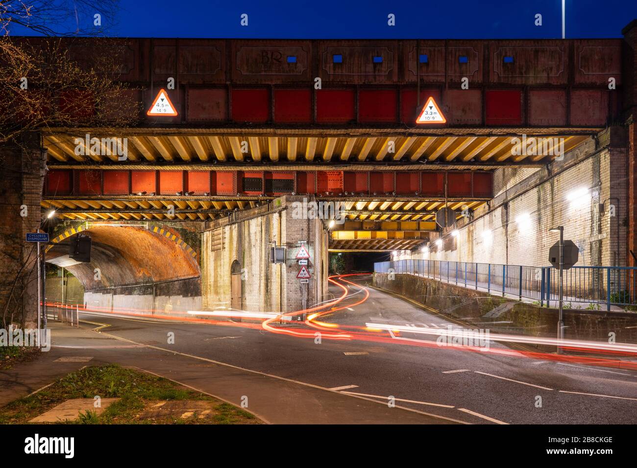 Light trails from vehicles under the Vyne Road / Chapel Hill railway bridge E1/135A on railway line BML1 in Basingstoke at night time. UK Stock Photo