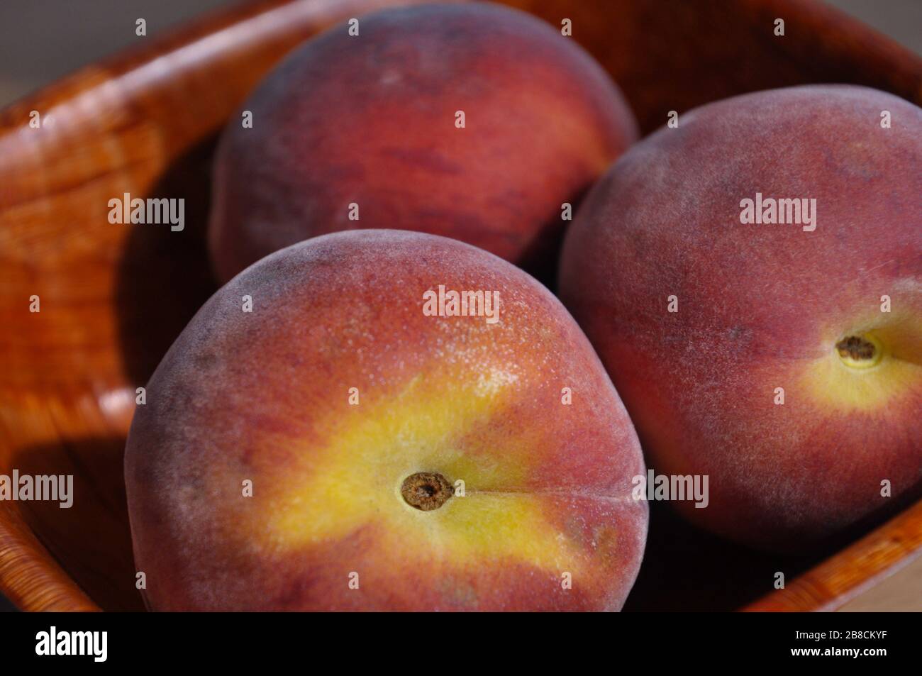 Still life with wooden bowl with three ripe peaches Stock Photo