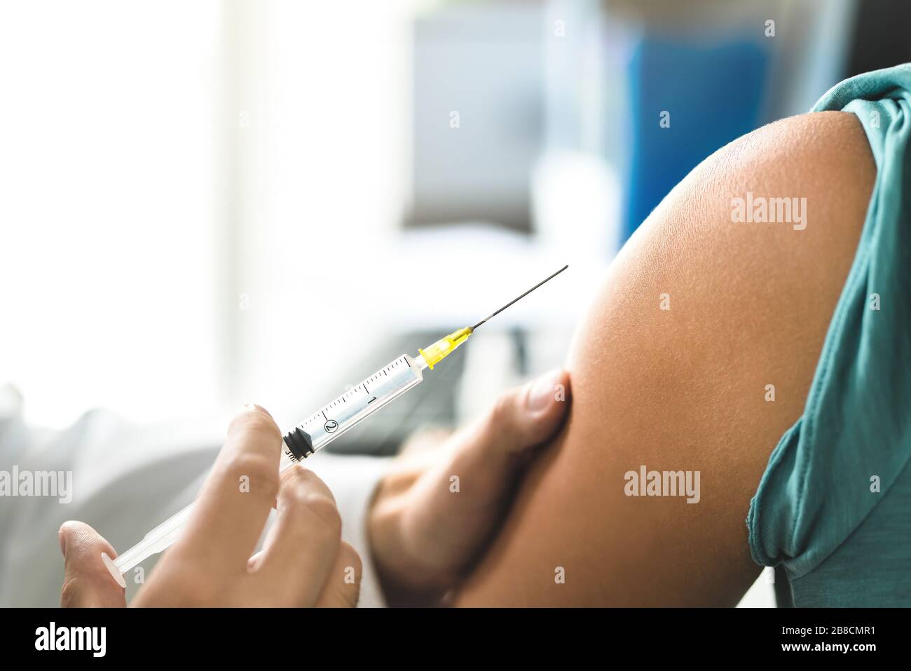 Doctor giving vaccine, flu or influenza shot  to patient with injection needle. Close up of arm and medical professional. Nurse or physician. Stock Photo