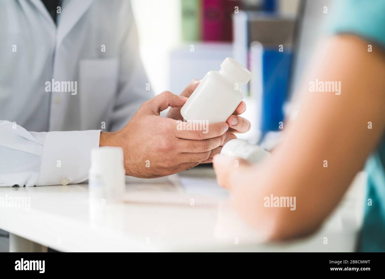 Doctor consulting patient about right medication. Physician holding medicine and pills in hand. Pharmacist in pharmacy in customer service. Stock Photo