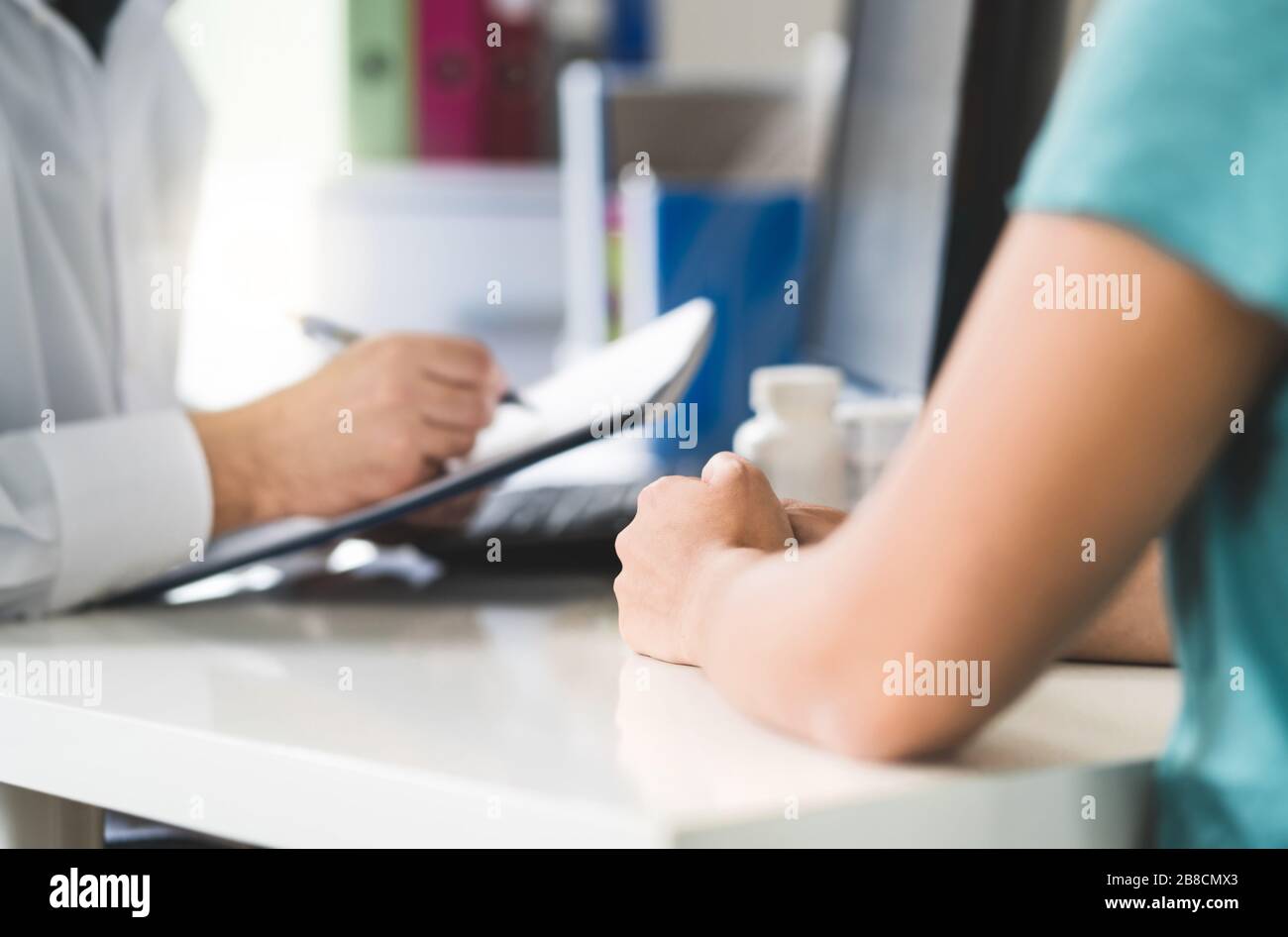 Sick patient visiting doctor in health care center or emergency room. Woman in appointment and meeting with physician or nurse. Stock Photo