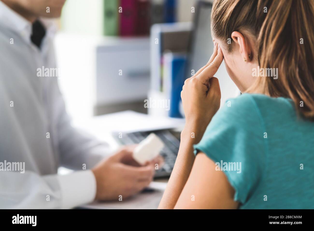 Doctor giving medical help to sick patient with bad headache or migraine. Physician or pharmacist holding bottle of pills and medicine in appointment. Stock Photo
