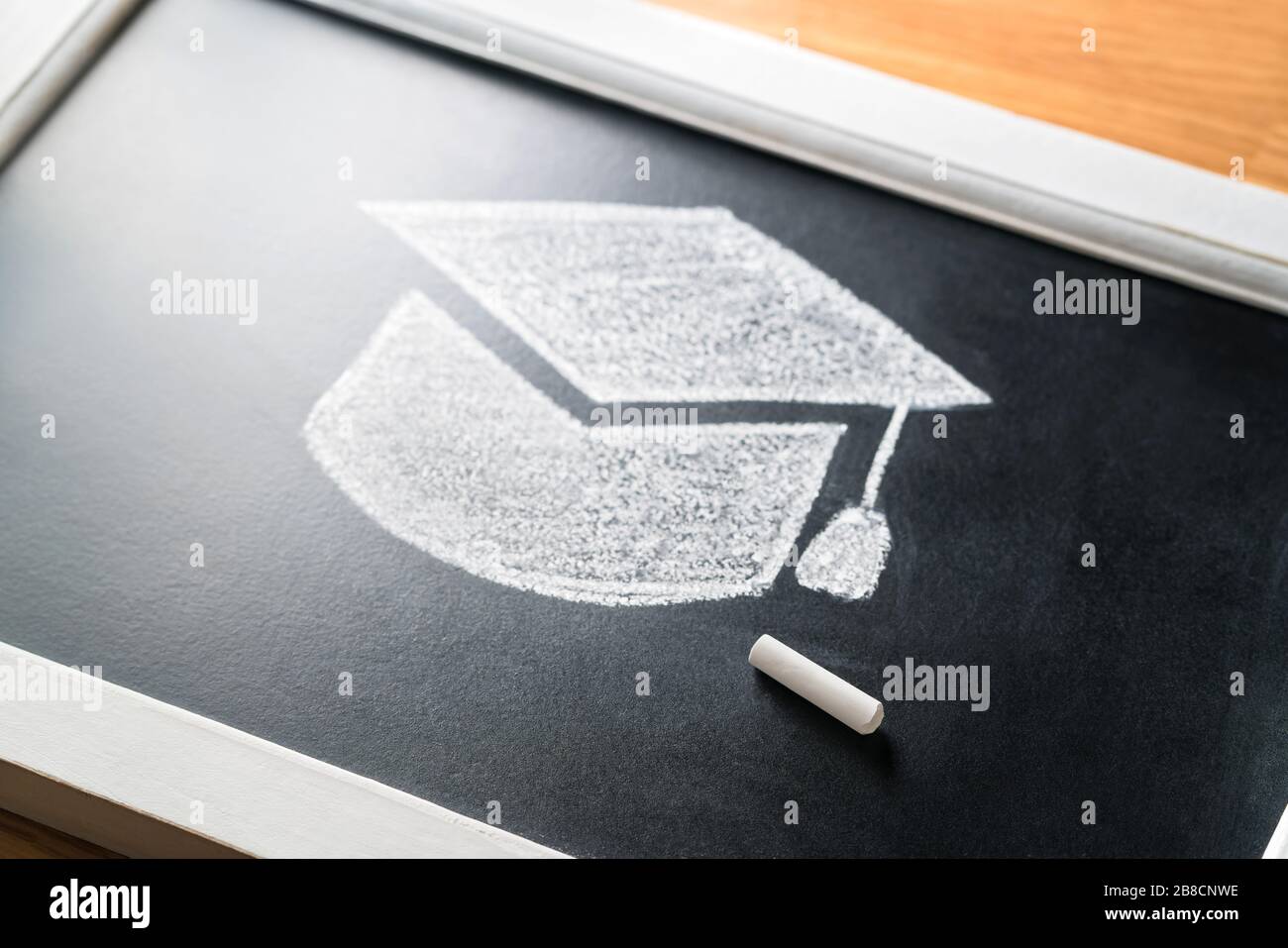 Graduation hat drawn on blackboard with chalk. Applying to college or university concept. Traditional education. Studying or teaching in classroom. Stock Photo