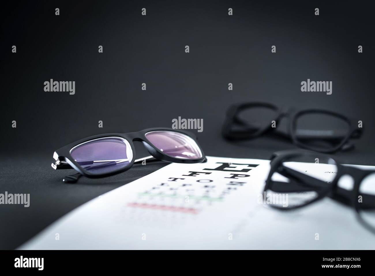 Glasses on eye sight test chart with different spectacle options on optician table. Ophthalmology or optometry clinic. Vision, eyesight. Stock Photo