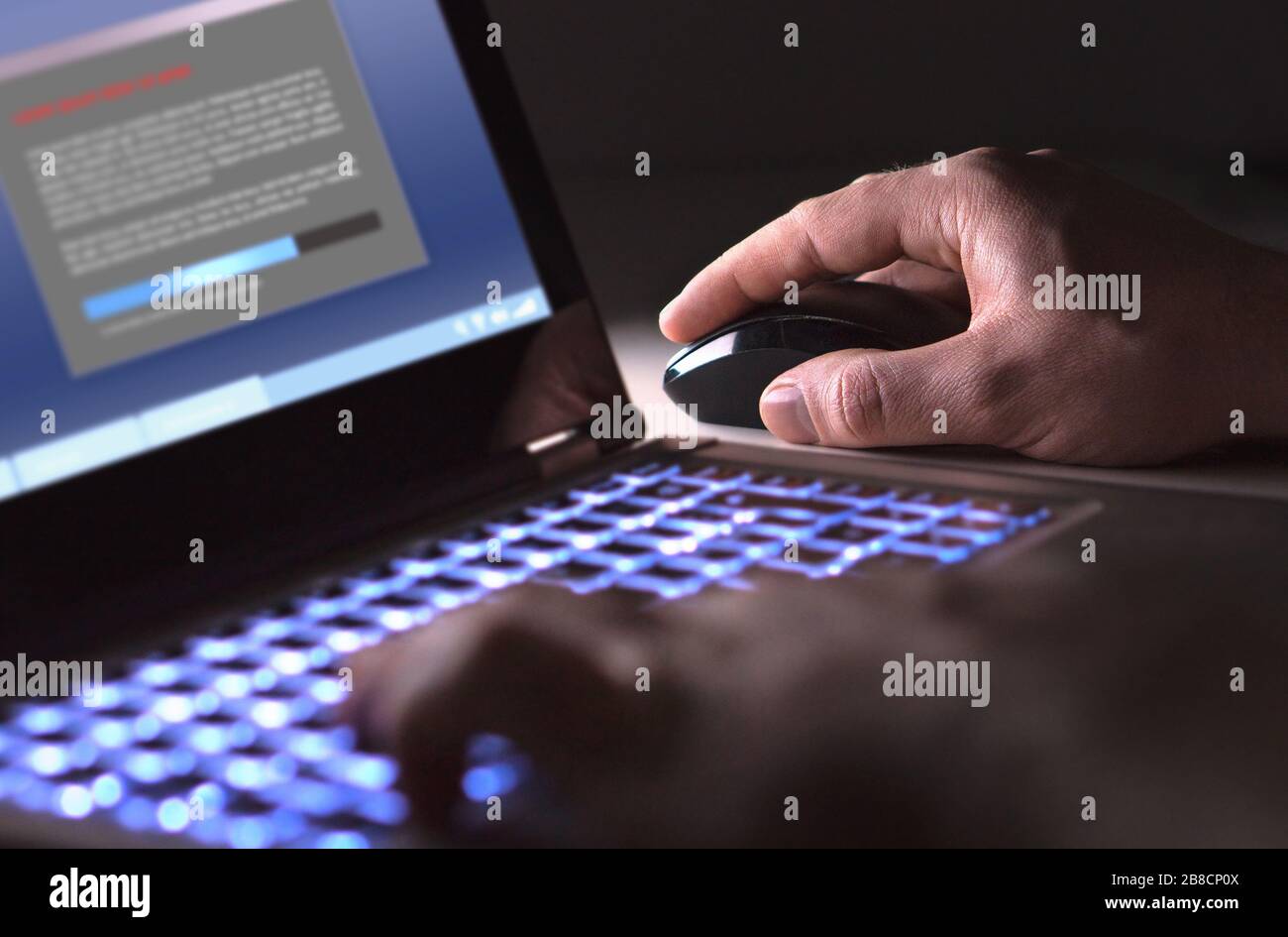 Man installing software in laptop in dark at night. Hacker loading illegal program or guy downloading files. Cyber security, piracy or virus concept. Stock Photo