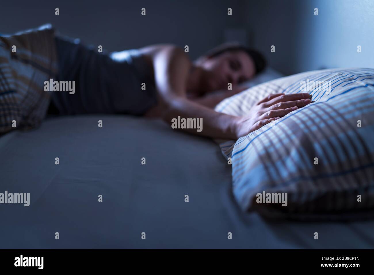 Single woman sleeping alone in bed at home. Lonely lady missing husband or boyfriend. Hand on pillow. Solitude, infidelity or heartbreak concept. Stock Photo