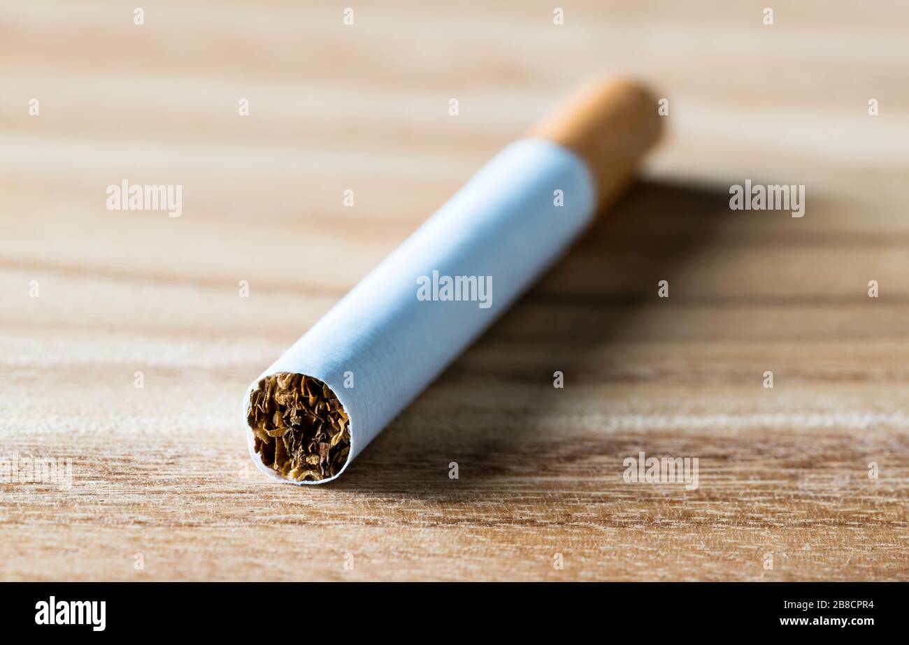 Cigarette on wooden table, macro close up view. Tobacco, paper and nicotine. Quit smoking. Stock Photo