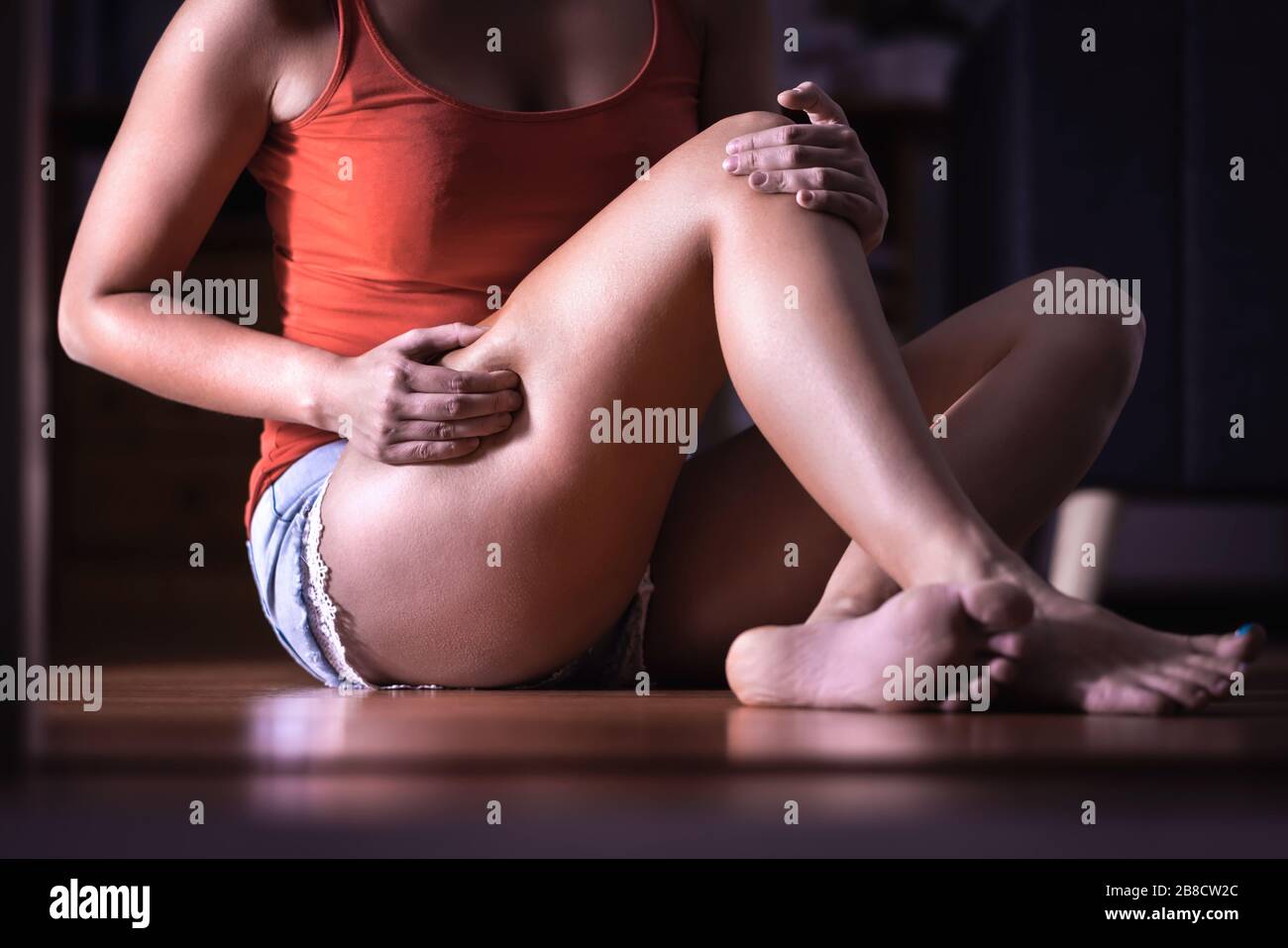 Young woman looking for fat, cellulite, imperfections or stretch marks in her leg and thigh. Girl searching flabby skin. Pressure and stress. Stock Photo