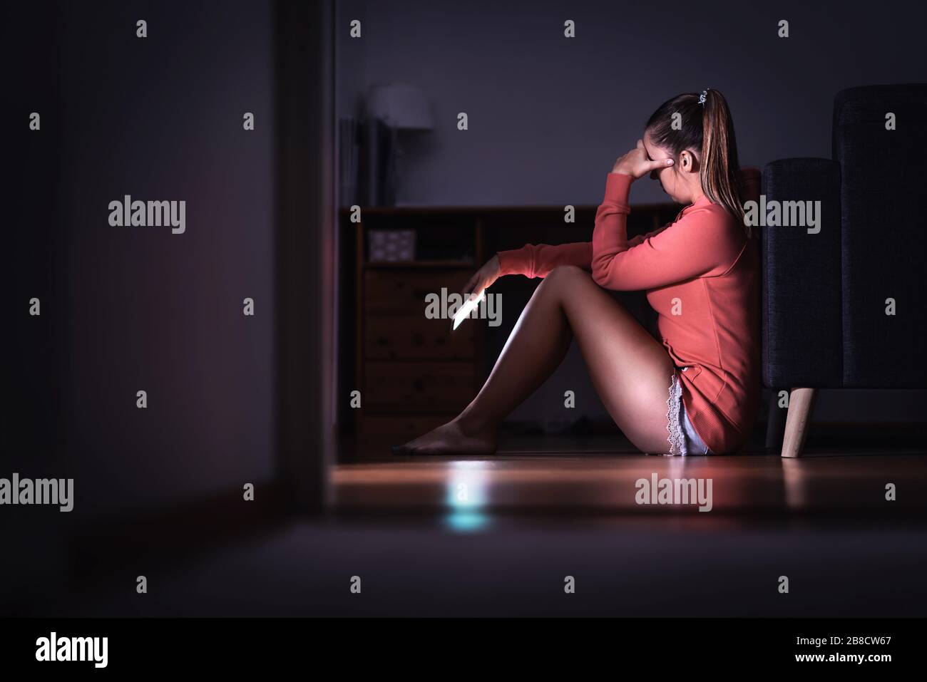 Sad woman with smartphone at night. Ashamed girl with stress, Desperate heartbroken person waiting for call. Cyber bullying. Break up. Stock Photo