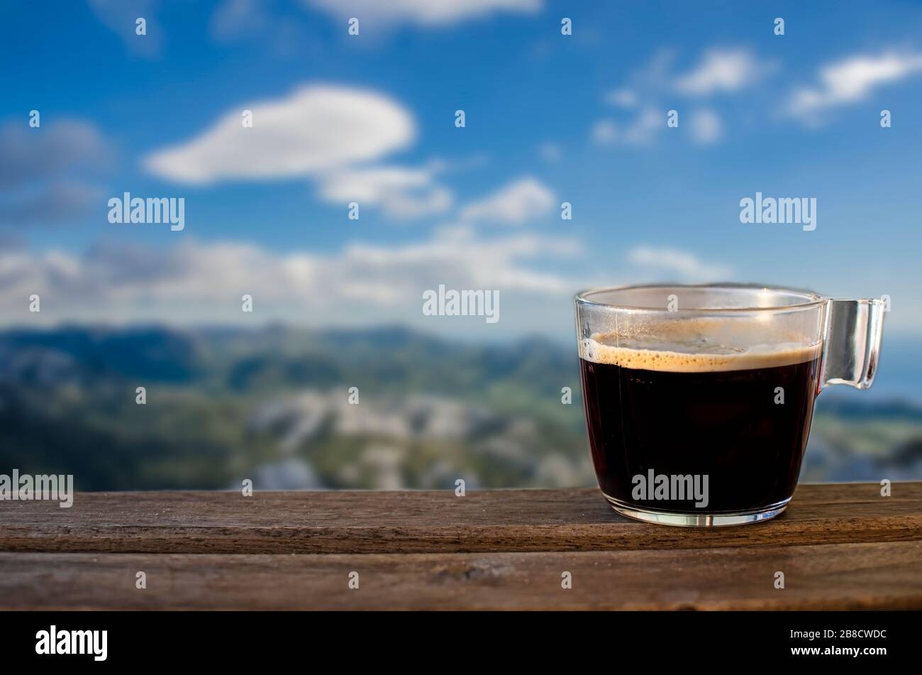 Cup of black coffee with blue sky and mountains background, Croatia. View of mountains, sky and sea in Northern Velebit National Park. Scenic mountain Stock Photo