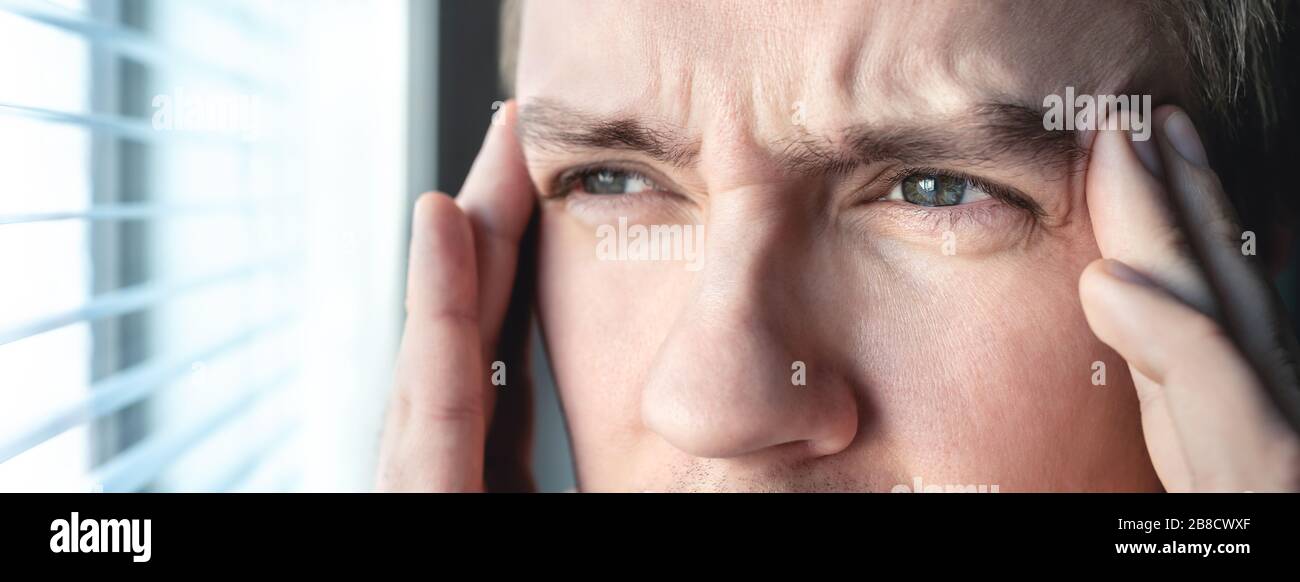 Serious man with stress. Ashamed or depressed person. Burnout, amnesia, memory loss or ptsd concept. Migraine or headache. Candid close up of guy. Stock Photo