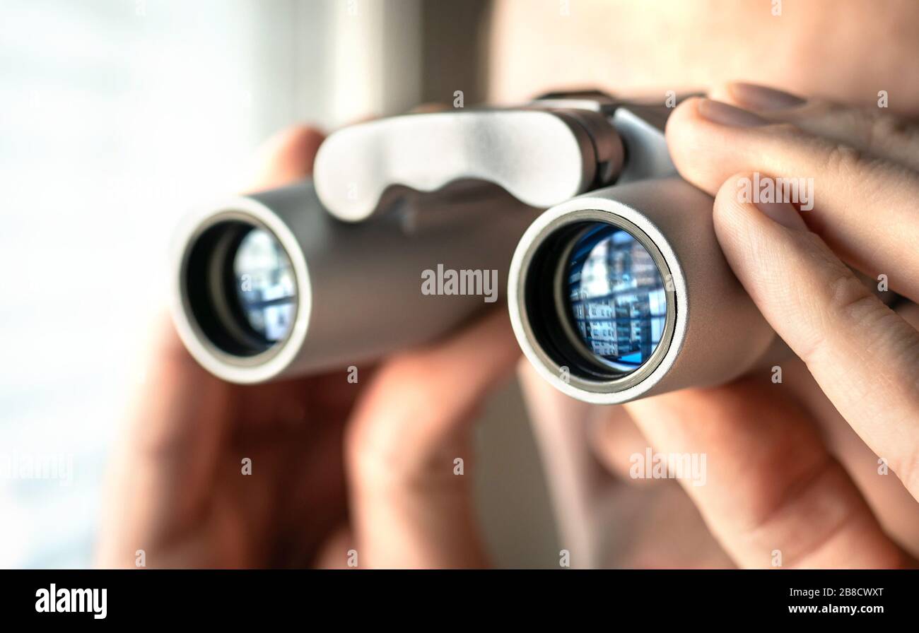 Man watching out the window with binoculars. Curious and nosy neighbour. Private detective or undercover cop investigating or spying. Curious person. Stock Photo