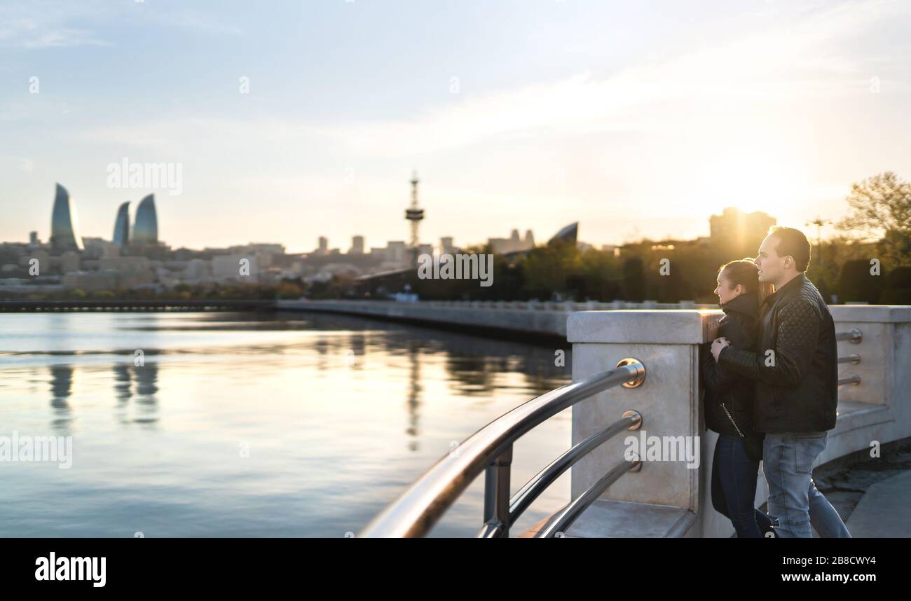 Couple in Baku at sunset looking at the sea. People on a holiday getaway. Happy man and woman on a date. Travel and tourism in Azerbaijan. Stock Photo