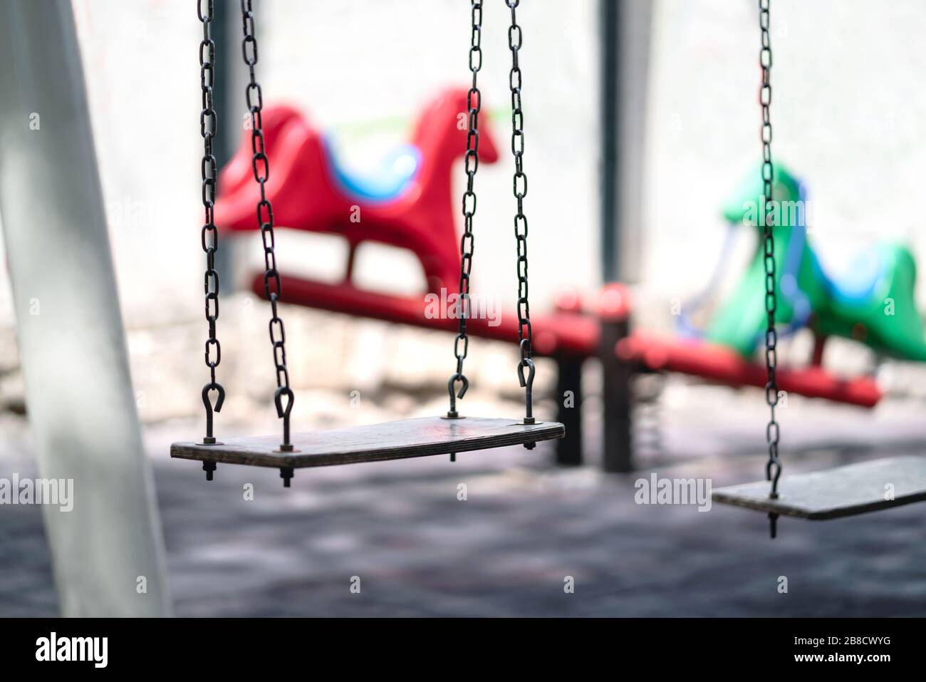 Empty swing at a playground. Sad dramatic mood for negative themes such as bullying at school, child abuse, pedophilia, traumatic childhood or kidnap. Stock Photo