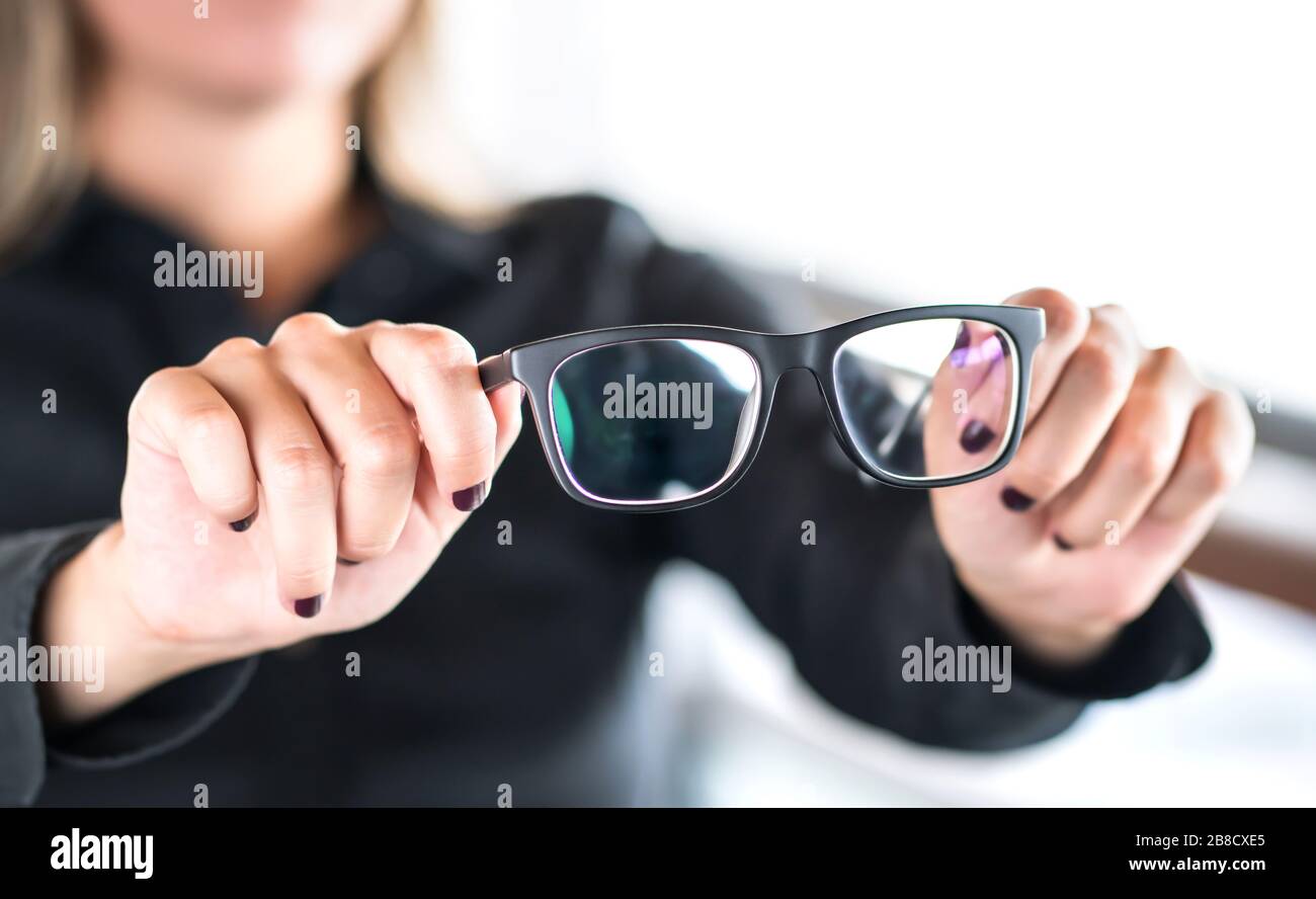 Woman holding new glasses. Lenses and spectacles getting fix and repair by professional optician. Optometrist, oculist or eye doctor in clinic. Stock Photo