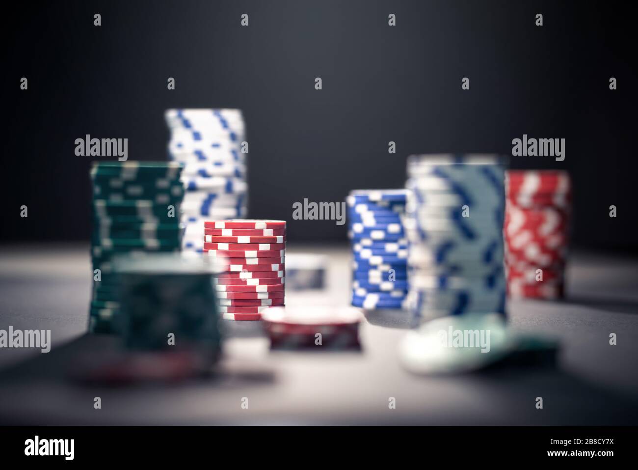Casino poker chips in dramatic dark shadow or at night in spotlight. Stack of game money. Risk, luck and betting concept. Gambling problem. Stock Photo