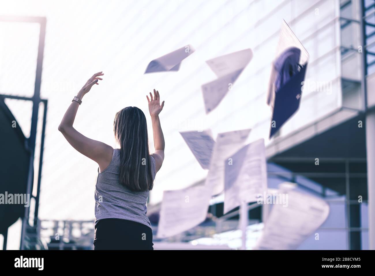 Business woman throwing work papers in the air. Stress from workload. Person going home or leaving for vacation. Employee got fired. Stock Photo