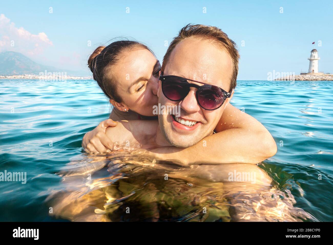 Couple taking selfie in water while swimming in the sea on holiday. Two happy people on fun family vacation. Romantic honeymoon in tropical summer. Stock Photo