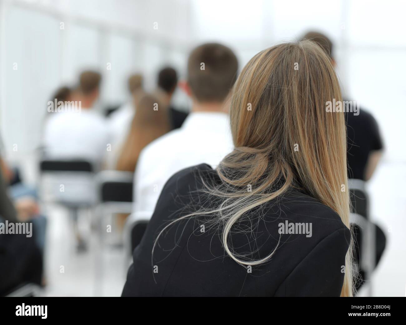 rear view. a group of diverse young people sitting in a conference room ...