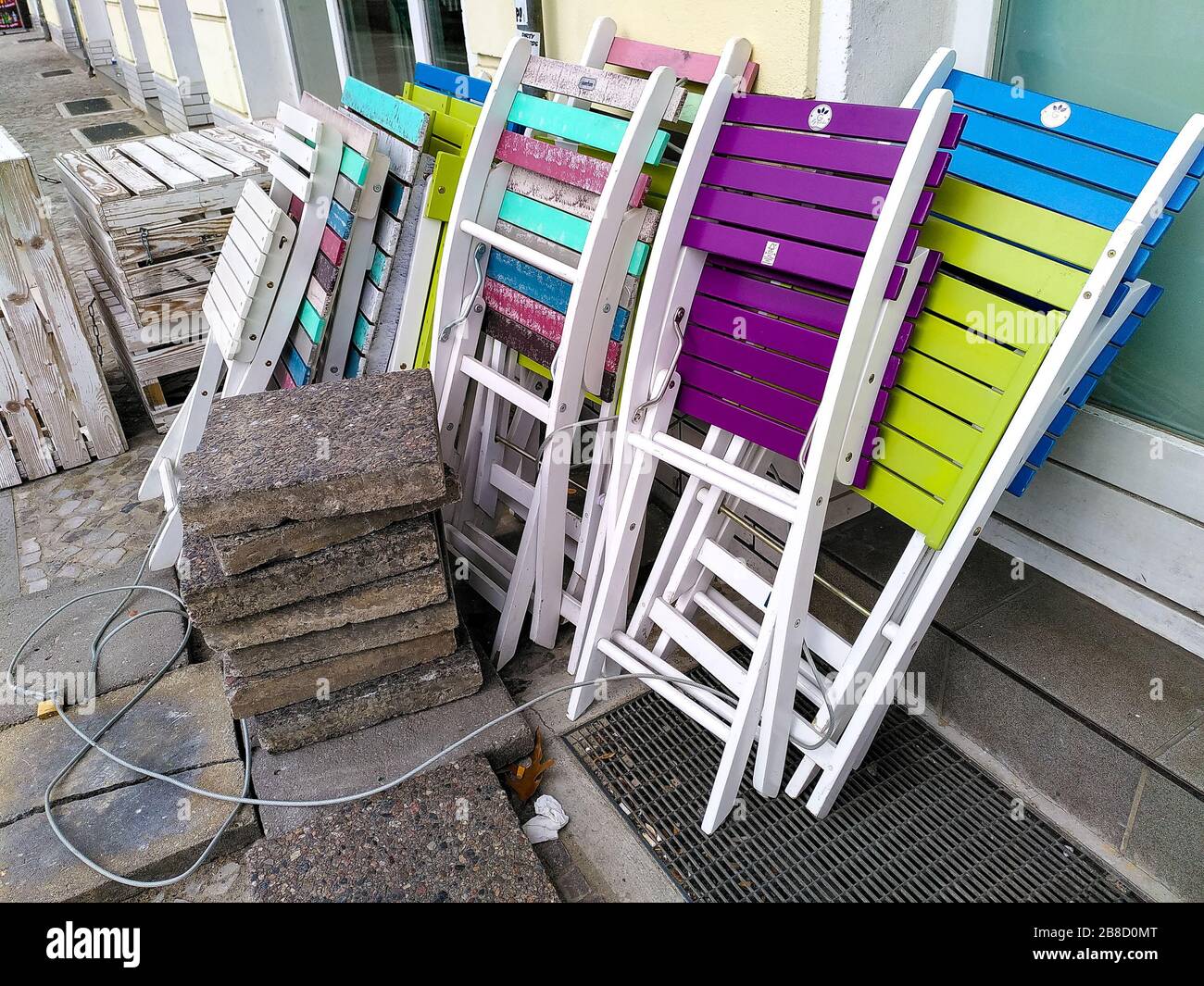 Folded up garden chairs and tables from a street restaurant in the Friedrichshain neighborhood of Berlin during coronavirus shutdown in Germany. Stock Photo