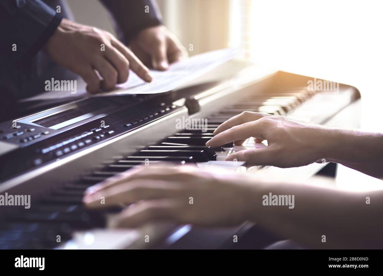 Piano teacher and student practising. Music lesson and course in school. Man learn playing with tutor in class. Mentor teaching pianist. Band practise. Stock Photo