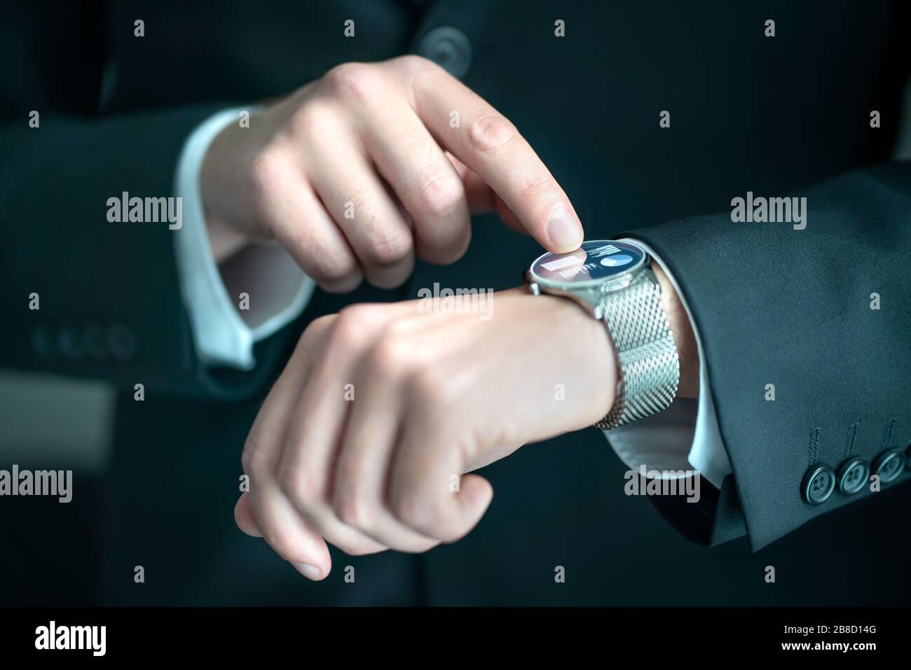 Businessman wearing smart watch with banking, finance or business report app. Man in suit using wearable gadget for work. Hybrid smartwatch. Stock Photo
