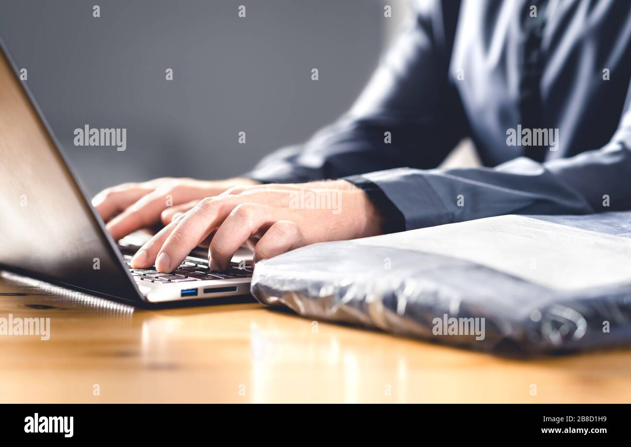 Return package after free shipping for online order. Wrong product from internet. Man writing complaint, claim or reclamation with laptop. Stock Photo