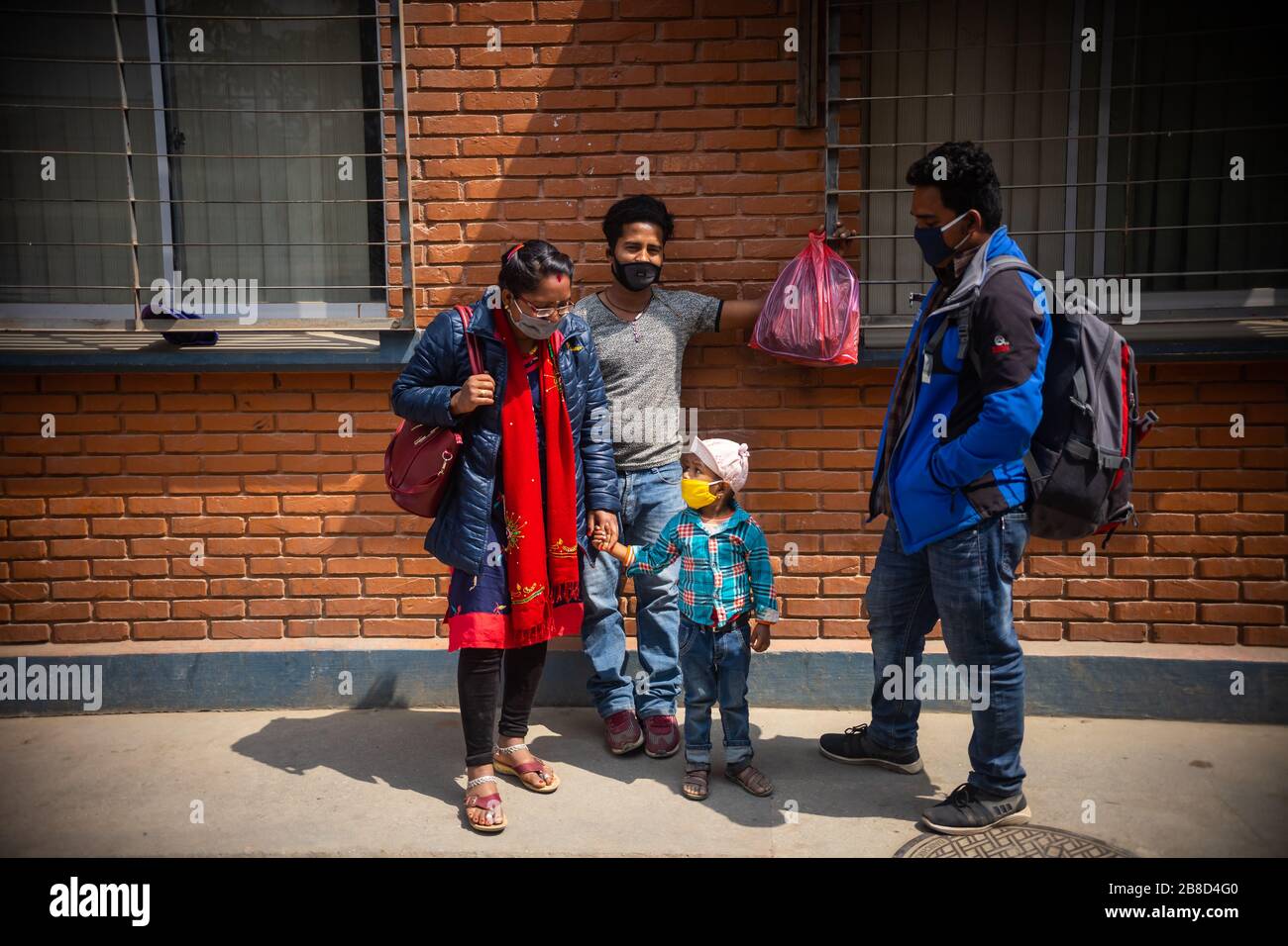 A family wearing medical masks as a preventive measure, waiting for tickets during the corona virus pandemic.Kathmandu's new bus park is crowded after government decides to halt long-tour vehicles amidst Covid-19 fears, effective from March 23 to March 31. The last three days saw over 500,000 leaving the capital. Stock Photo