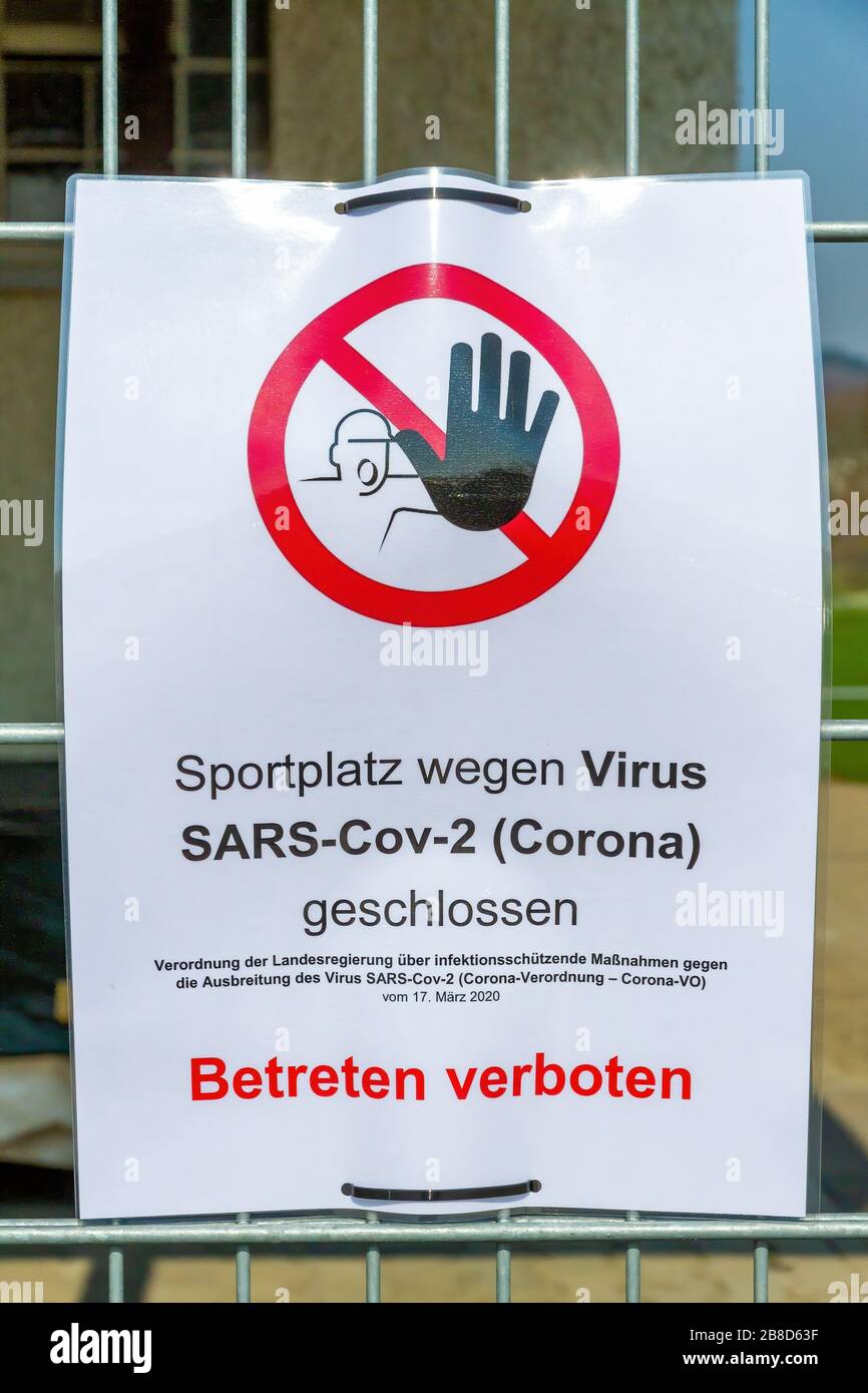 Warning Sign on playing field with graphic and german text 'Closed Playing field concerning Coronavirus - Beware of trespassing' Stock Photo