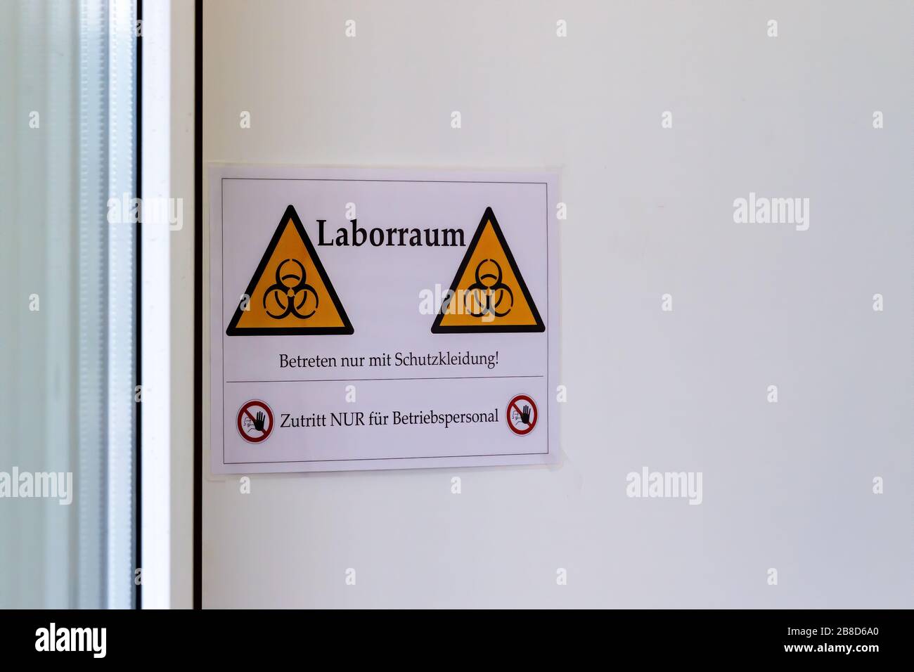 Bio Hazard sign on a door of a laboratory - Coronavirus Test. ( German Text on the Sign: laboratory space, enter only with protective cloting, Beware Stock Photo