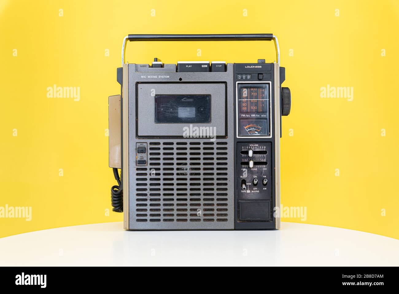 Dirty old 1970s style cassette player radio against a yellow background. Stock Photo