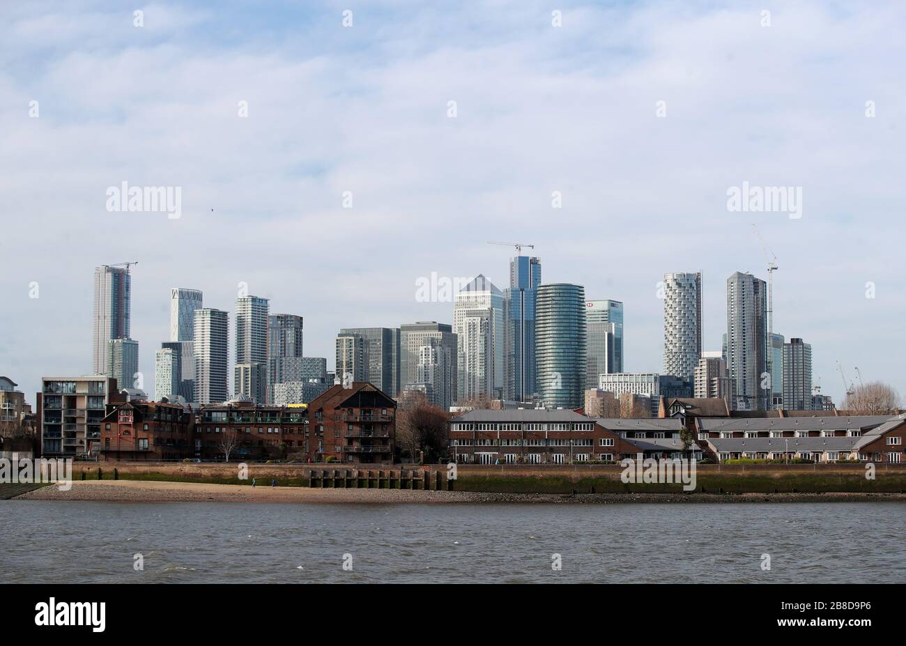 A view across the River Thames of the financial district in Canary Wharf in London after Prime Minister Boris Johnson ordered pubs, cafes, nightclubs, bars, restaurants, theatres, leisure centres and gyms to close to fight coronavirus. Stock Photo
