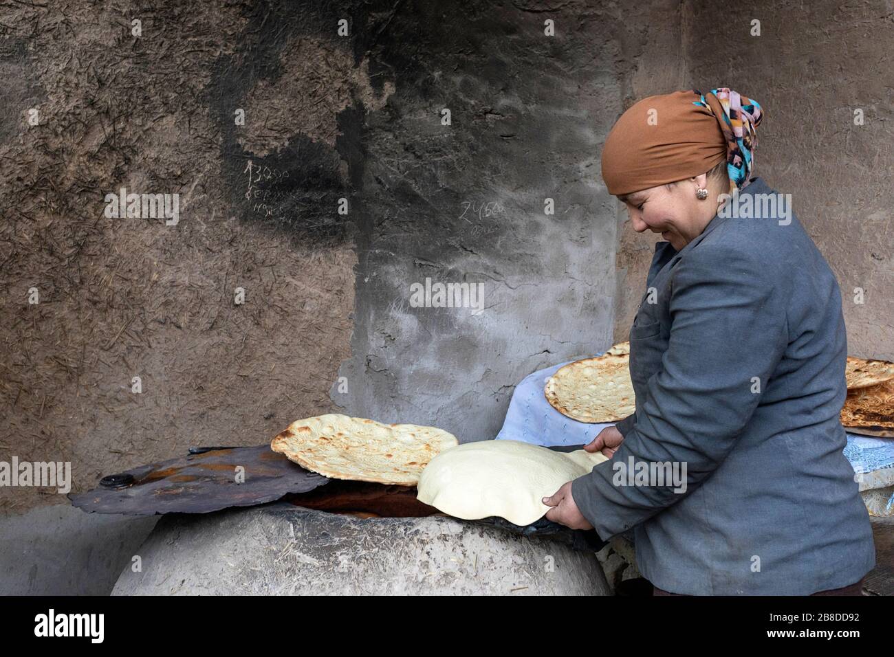 A Local Woman Bakes traditional Bread In A Traditional Clay Oven, Khiva, Uzbekistan Stock Photo