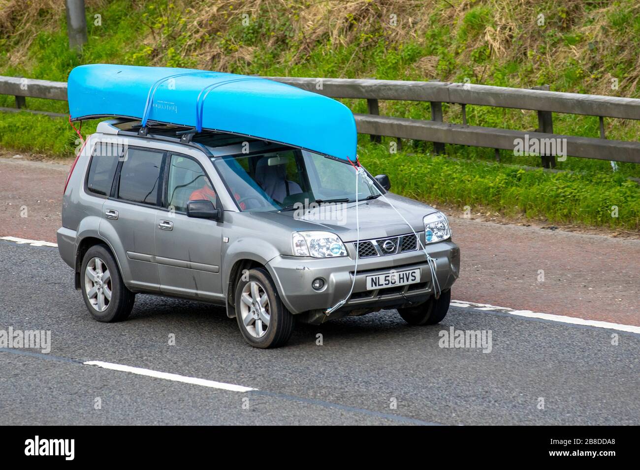 2006 silver Nissan X-Trail Columbia DCI car carrying leisure equipment consisting of kayaks and canoes on roof rack travelling on the M6. UK Stock Photo