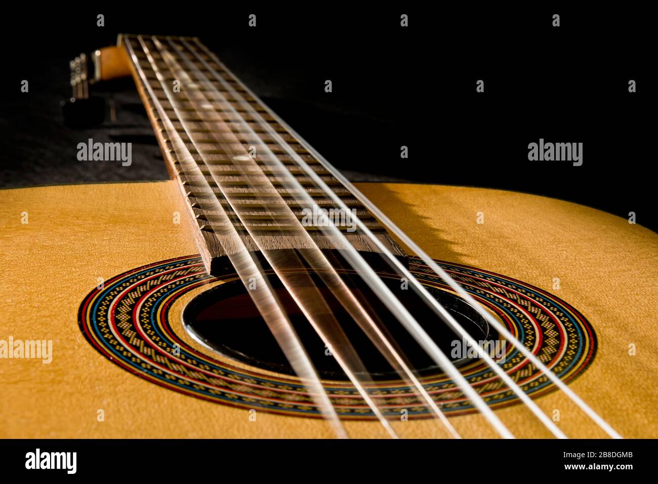 Classical guitar with vibrating strings on a black background Stock Photo -  Alamy
