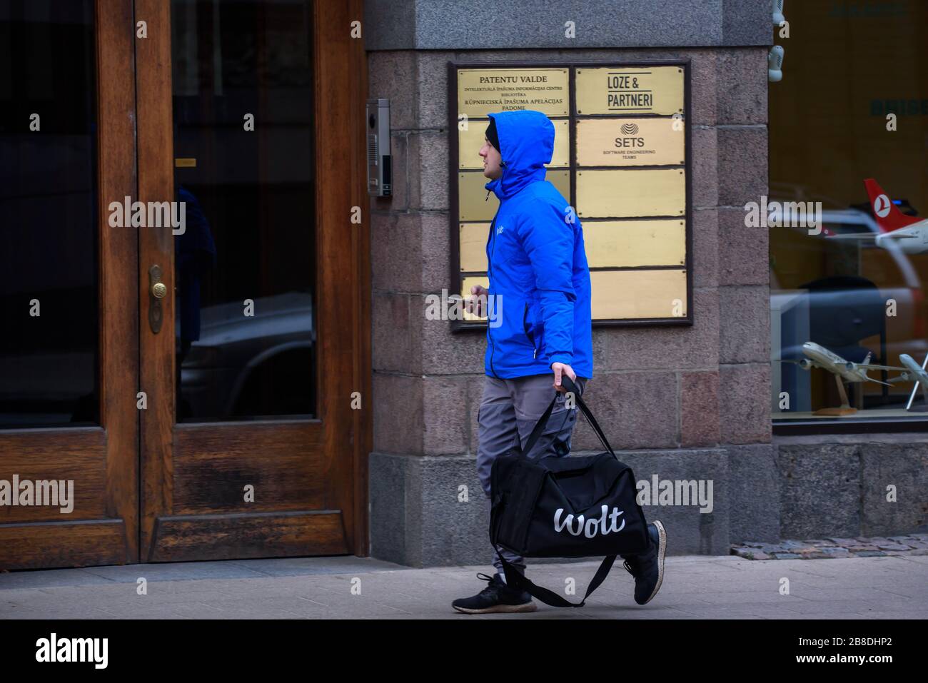 RIGA, LATVIA. 25th November 2019. Wolt company food delivery worker walks with food bag in Riga city. Wolt is Finnish technology company that is known for its food-delivery platform. Stock Photo