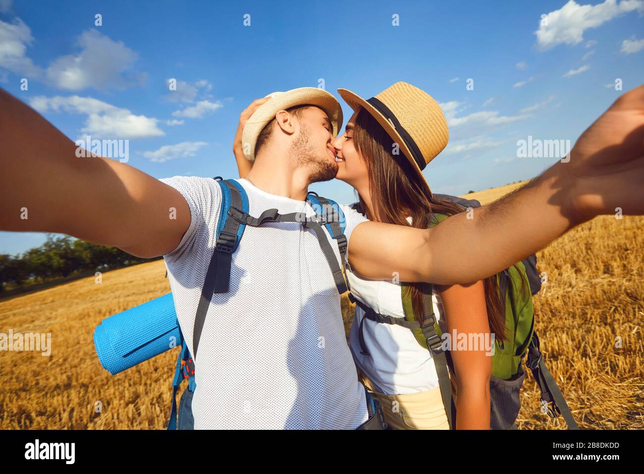 Couple of travelers with backpacks makes selfie photo on the phone on the nature. Stock Photo
