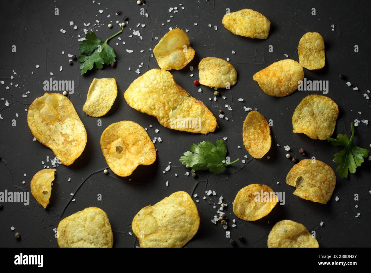 potato chips, pepper mixture, sea salt on a dark table Stock Photo