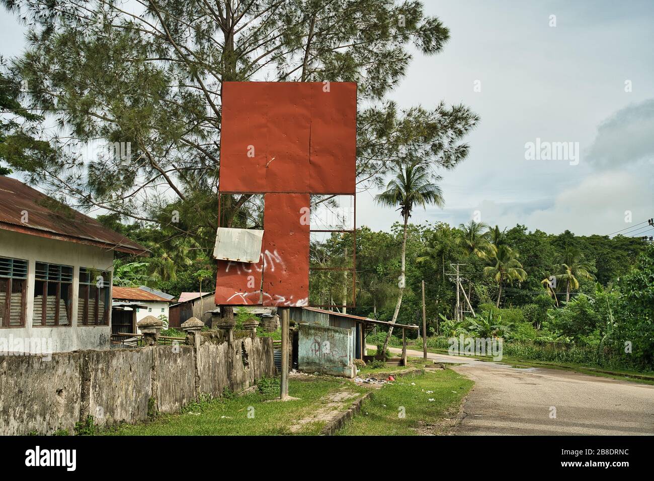 Old, incomplete and dilapidated terracotta red billboard free of advertising on a crowded street in a jungle town. Stock Photo
