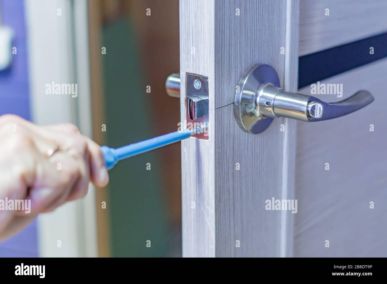 man repairing the doorknob with screwdriver. worker's hand installing