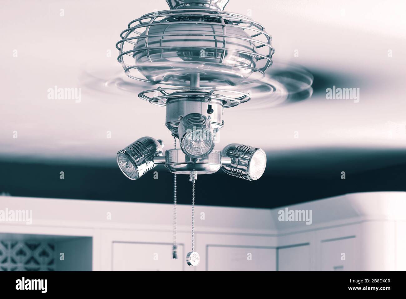 Ceiling fan light fitting with blades spinning in a kitchen. With
