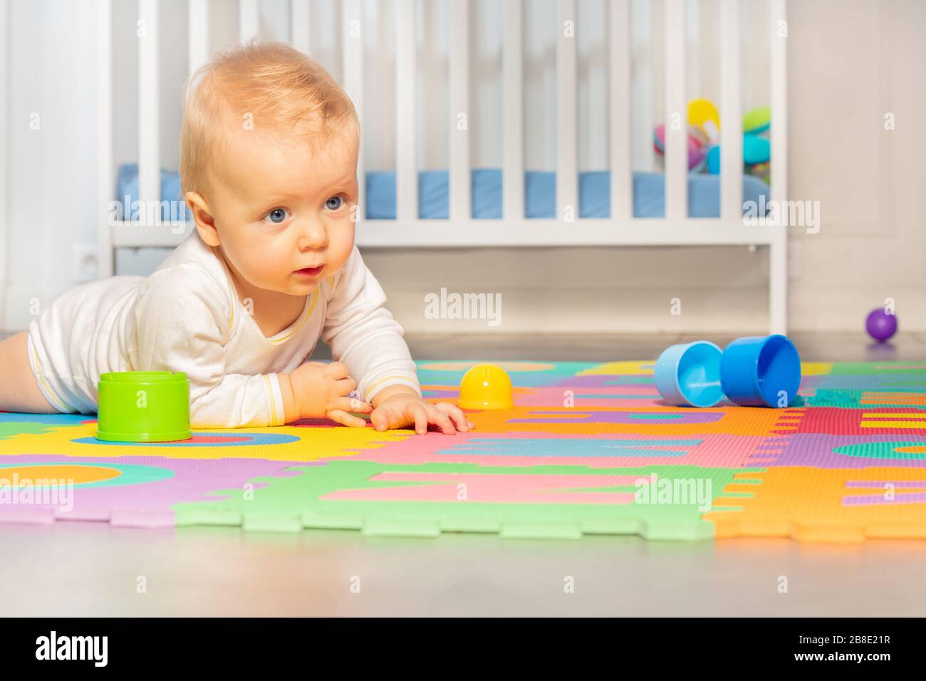 Beautiful baby toddler crawl on the floor of nursery grabbing toys near
