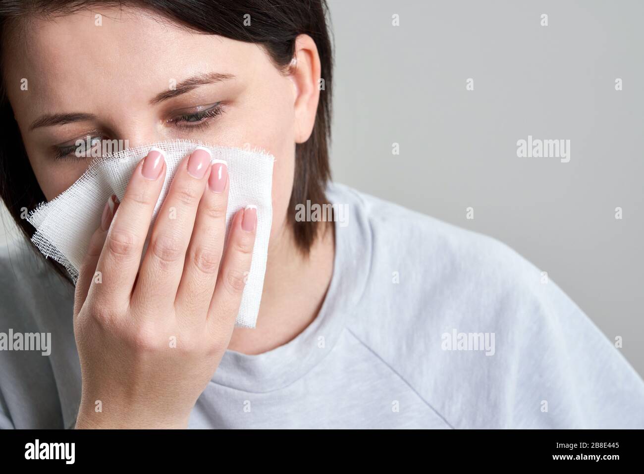 Young woman holding gauze or bandage instead of medical face mask to protect from coronavirus