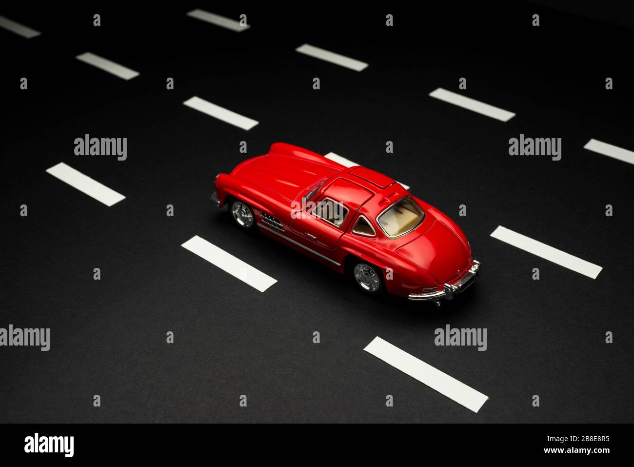 Izmir, Turkey - July 28, 2019: Mercedes 300 SL Red colored toy model car on an asphalt road with road lanes. Stock Photo